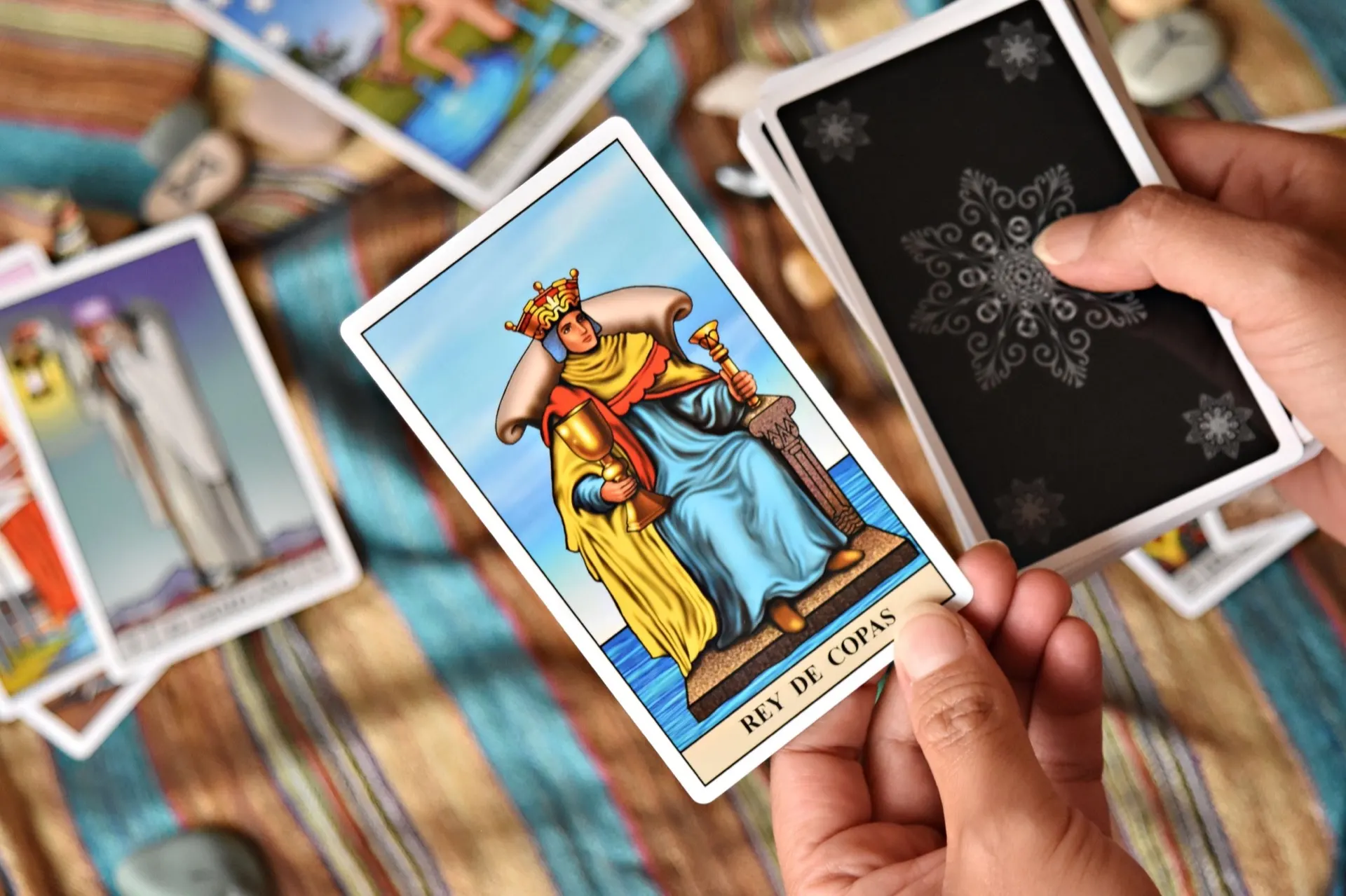 Cartes de tarot tenues en main au-dessus d'un tapis