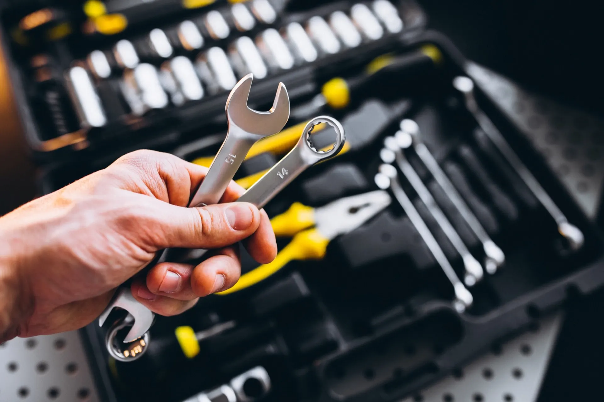 Main tenant des clés à molette au-dessus d'une caisse à outils